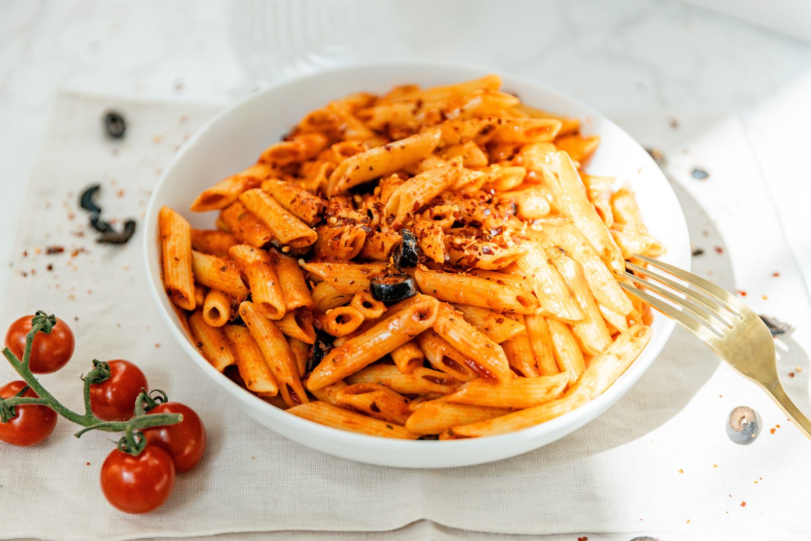 Penne arrabbiata in a white bowl with cherry tomatoes — Pastaphony Huntington Beach, opening November 2026